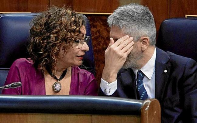 Grande-Marlaska se oculta el rostro mientras conversa con la ministra María Jesús Montero. | FOTO: E. P.