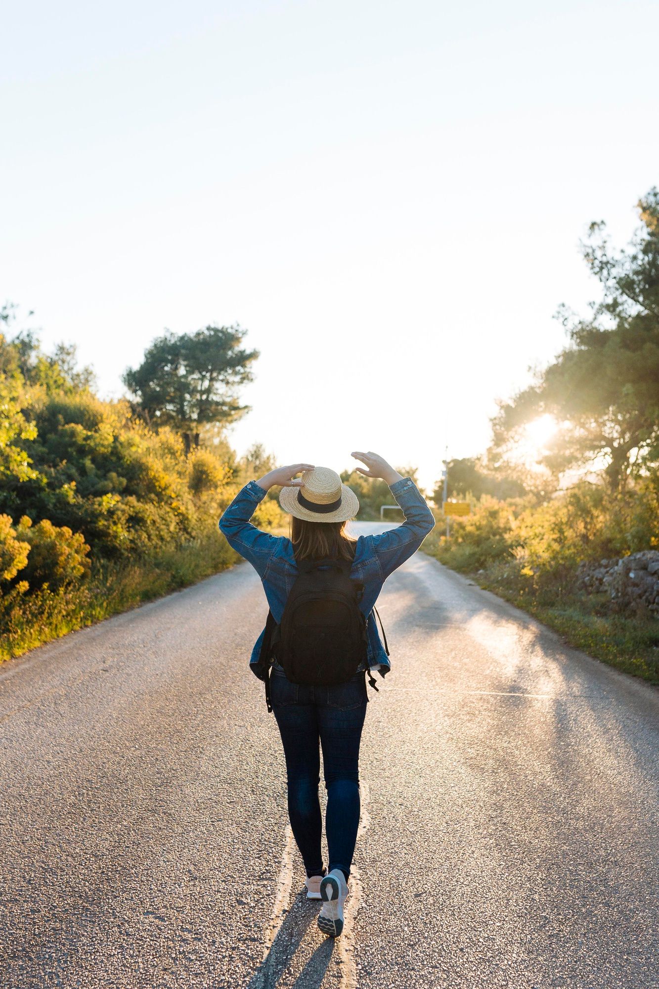 Una mujer camina por una carretera al atardecer.