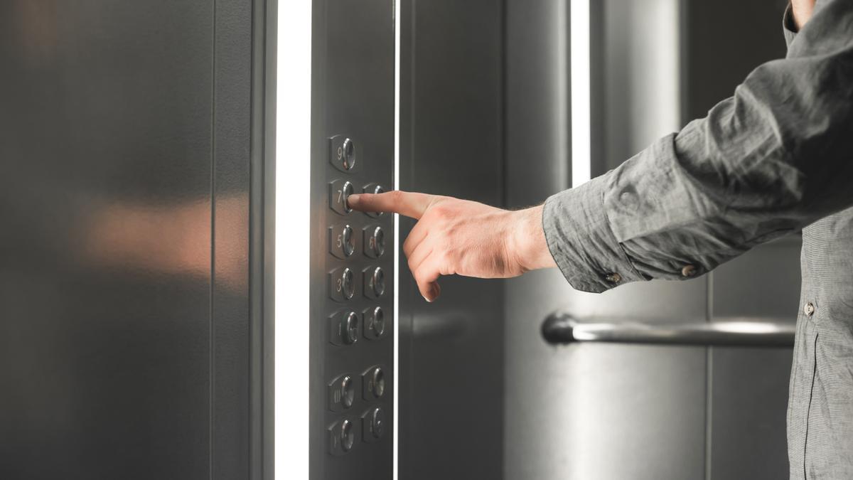Una persona pulsa un botón en el ascensor.