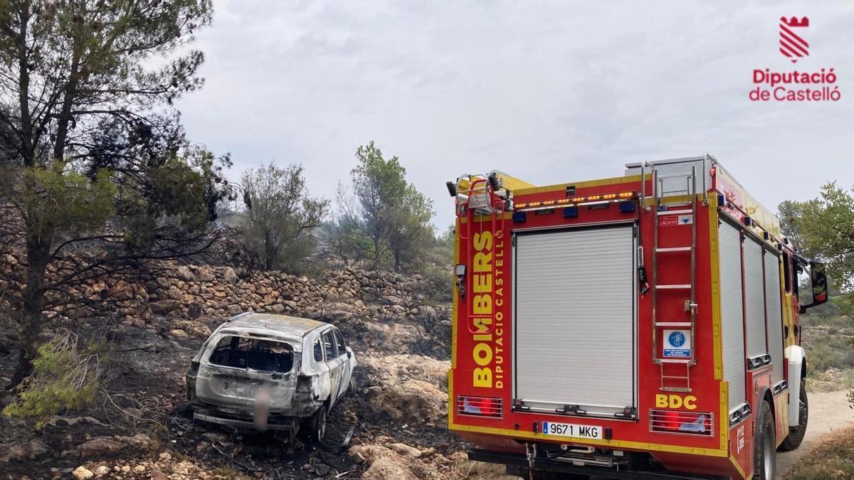 Un camión de bomberos de Castellón junto al vehículo calcinado.