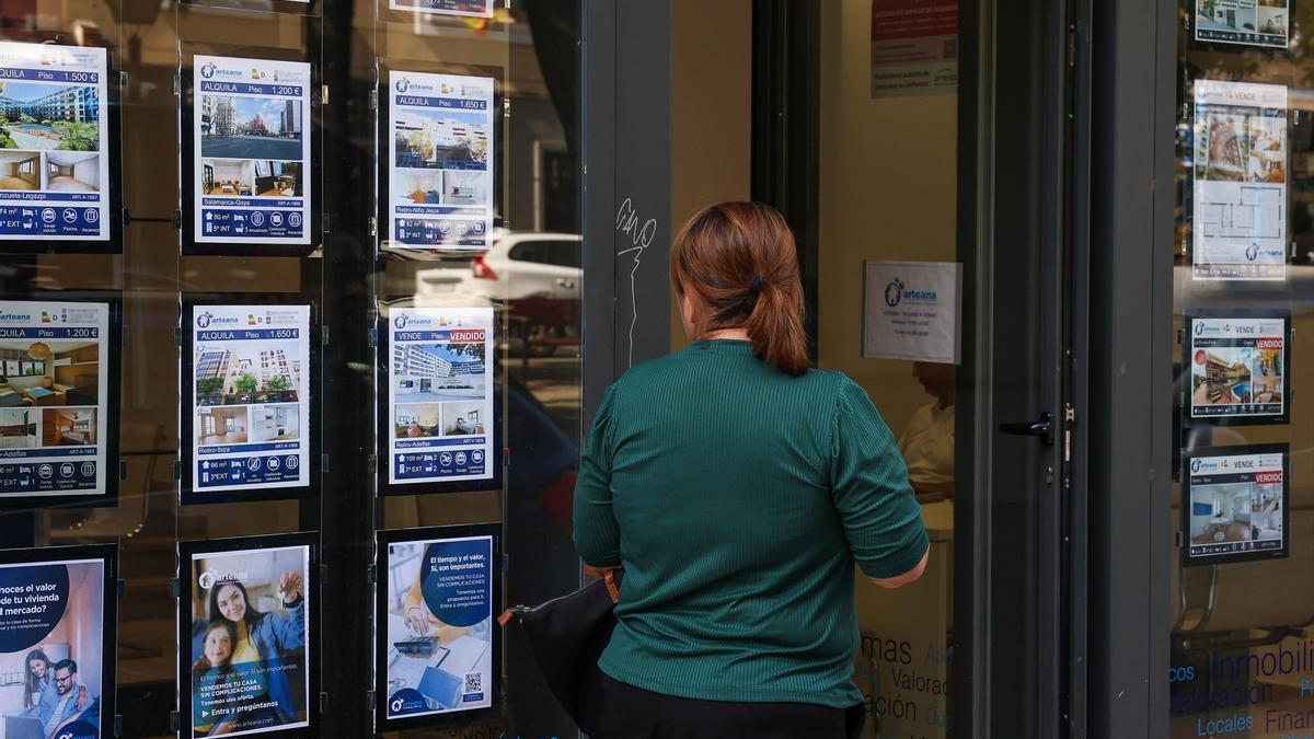 Una joven observa el escaparate de una inmobiliaria.