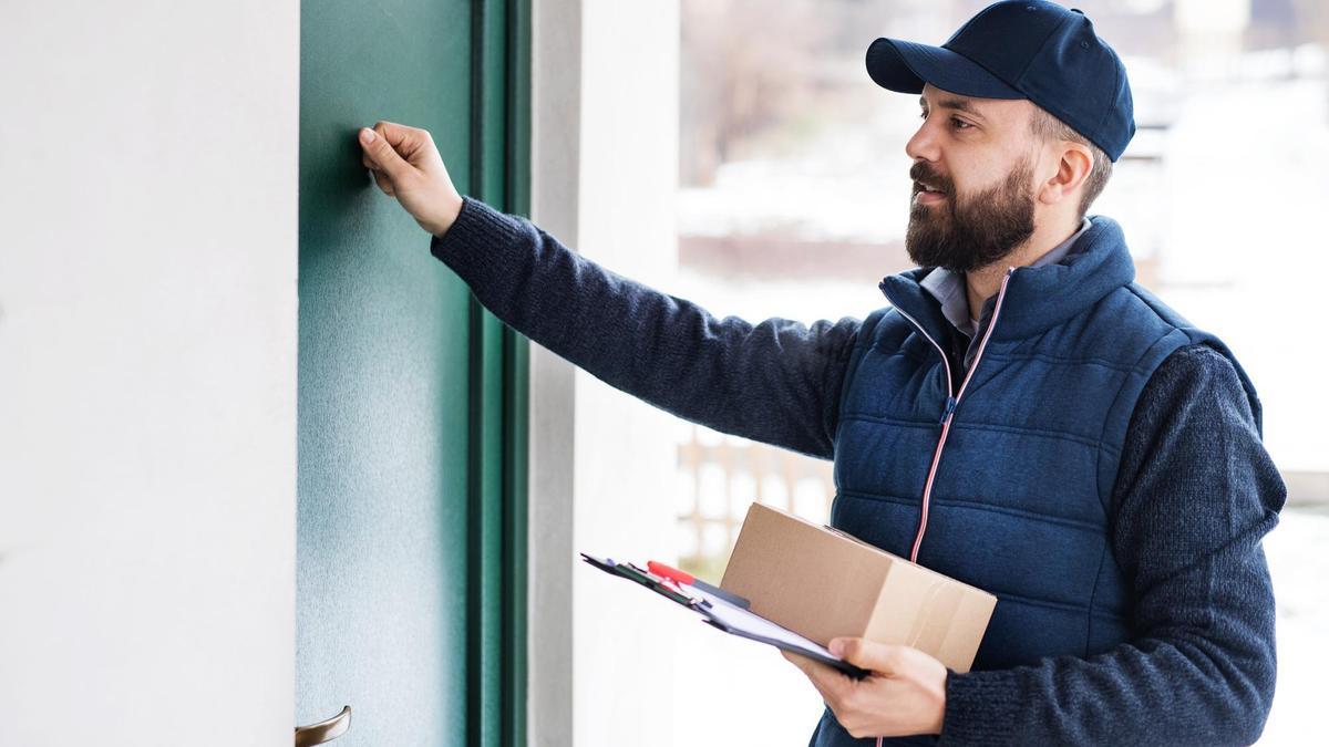 Un mensajero intenta entregar un paquete en un domicilio.