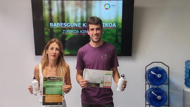 La alcaldesa Izaro Elorza y el edil Iker Oñati muestran el mapa de refugios climáticos y la botella que se reparte en la recepción de Zubikoa, el Servicio de Atención Ciudadana del Ayuntamiento y la Kultur Etxea