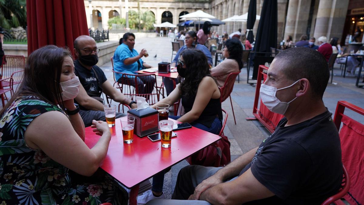 Varias personas con mascarillas toman una consumición en una terraza.