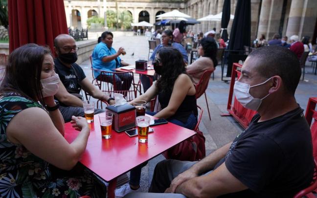 Varias personas con mascarillas toman una consumición en una terraza. Varias personas con mascarillas toman una consumición en una terraza.