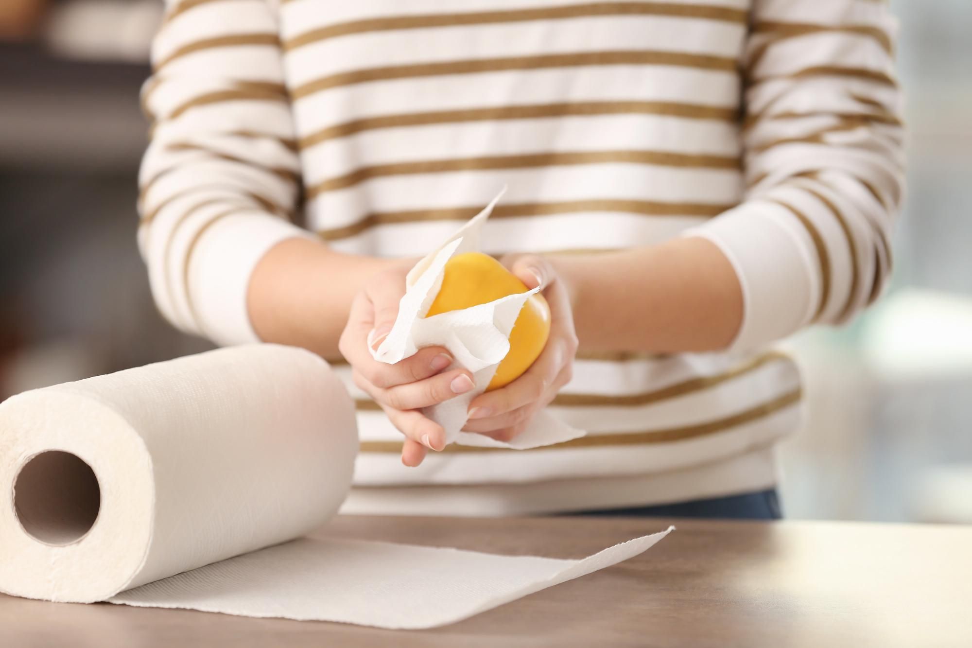 Una mujer limpia una manzana con papel de cocina.