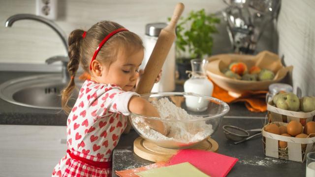 Una niña cocinando con las manos en harina