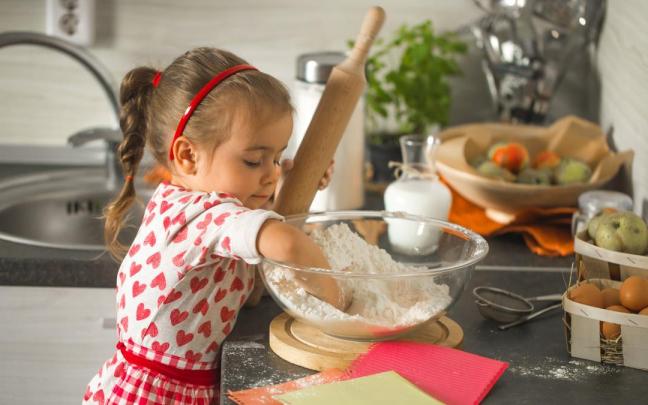 Una niña cocinando con las manos en harina