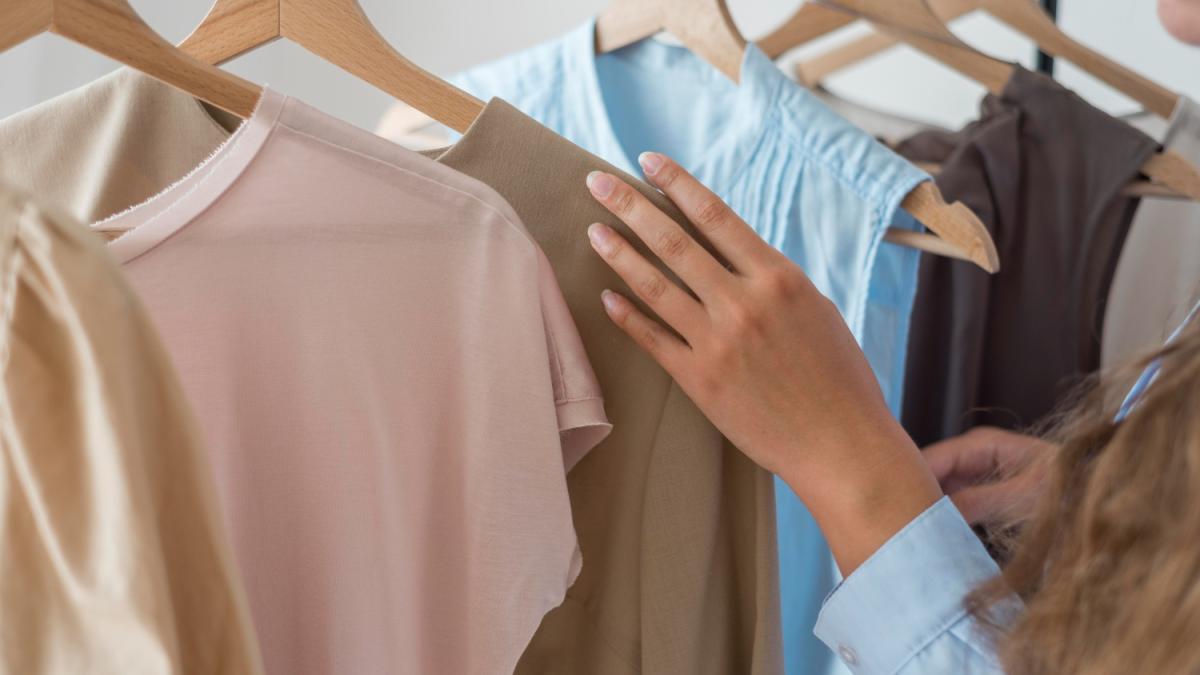Imagen de archivo de una persona escogiendo ropa en una tienda. FREEPIK