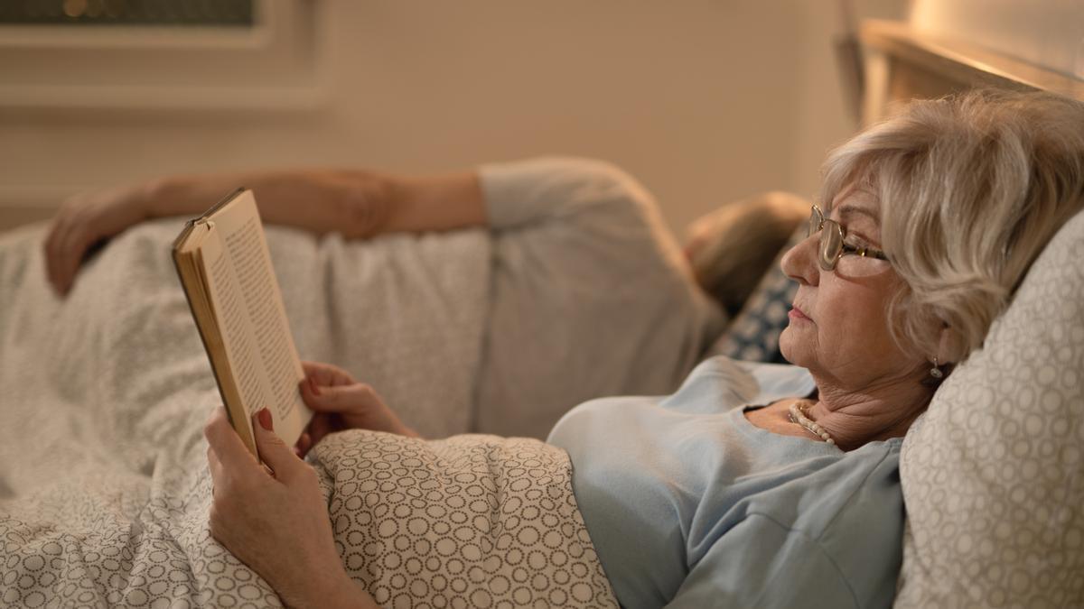 Señora lee un libro en la cama antes de dormir.