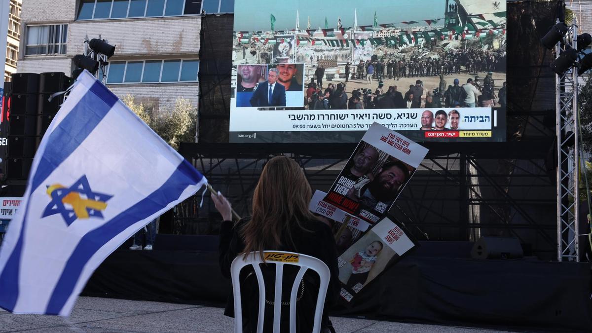 Una mujer sigue desde Tel Aviv la retransmisión de la puesta en libertad de rehenes israelíes.