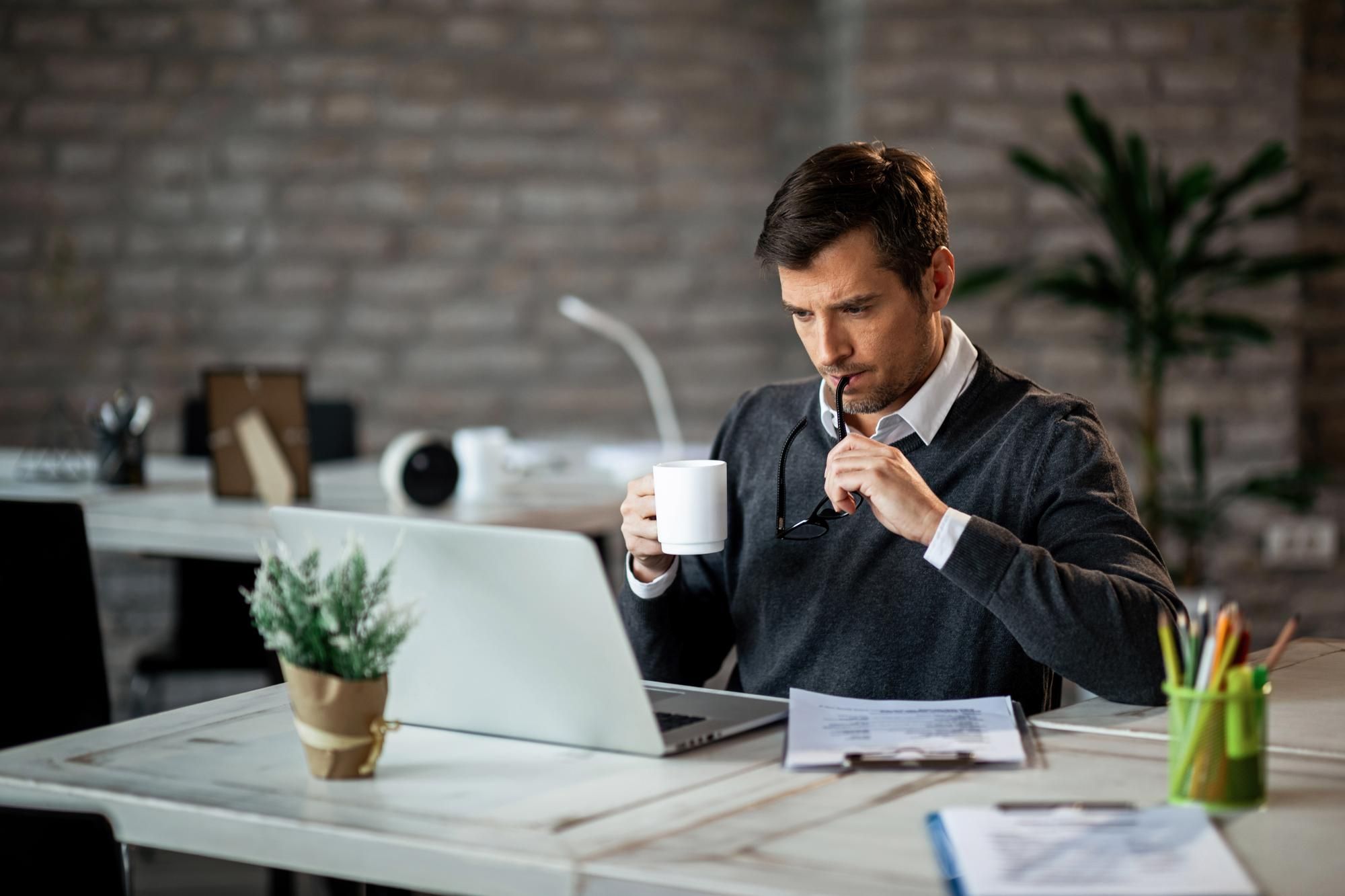 Un hombre toma un café mientras desempeña su trabajo.