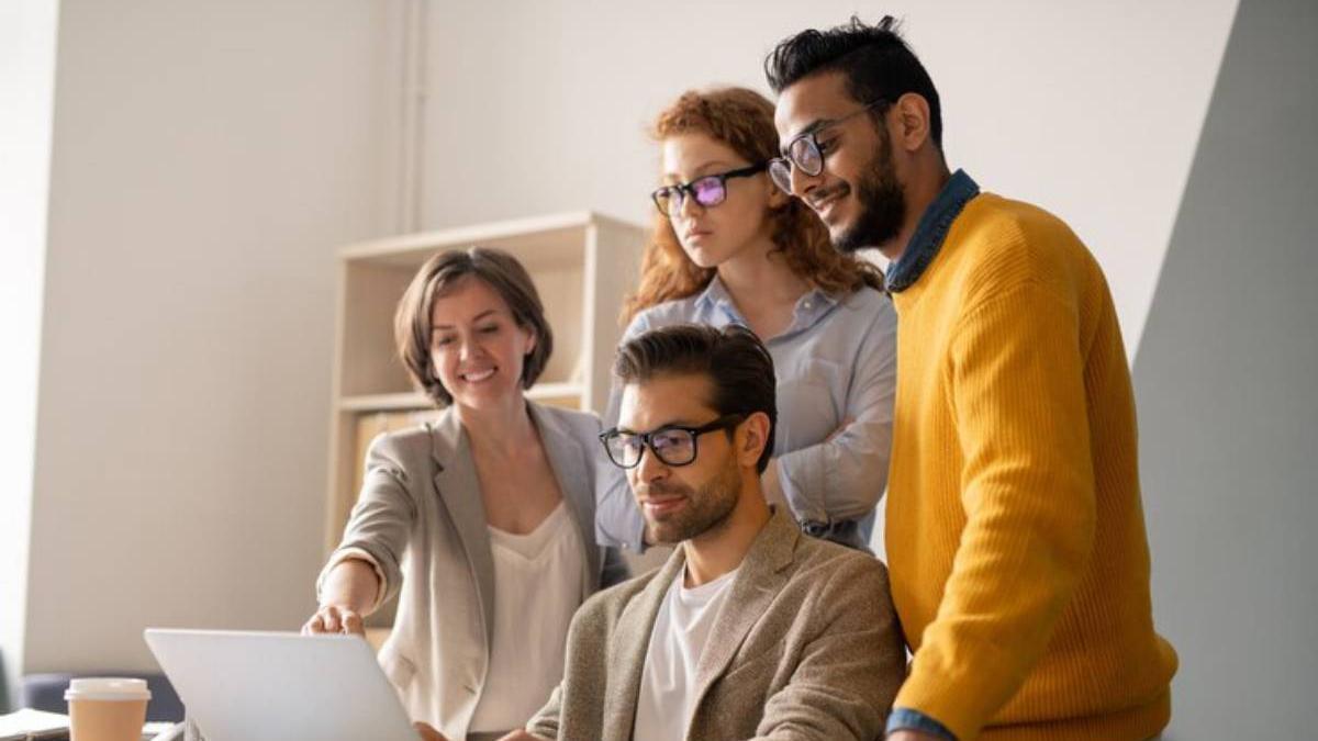 Compañeros de trabajo se ayudan entre ellos y comparten sus conocimientos en la oficina generando un excelente ambiente laboral.