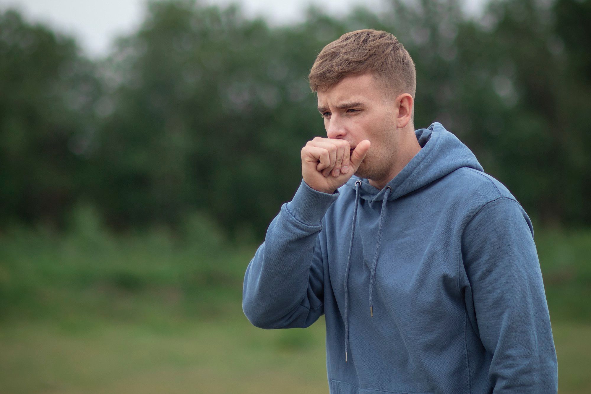 Un hombre tose para tratar de expulsar una flema.