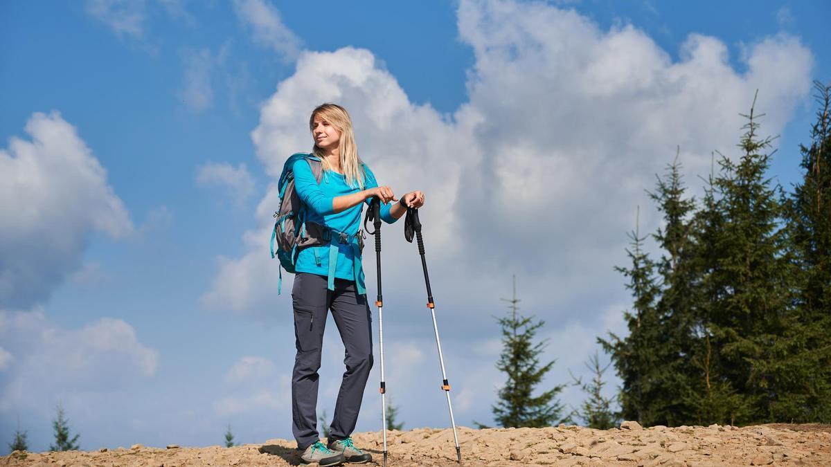 Una mujer disfruta de una caminata equipada con bastones de trekking.