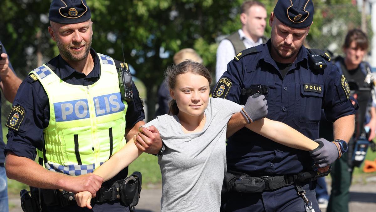 Greta Thunberg camina reducida por dos policías tras una acción en el puerto de Malmö