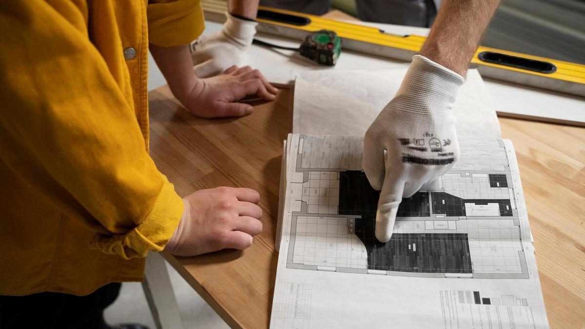 Trabajador y cliente miran un plano durante la reforma de un apartamento.