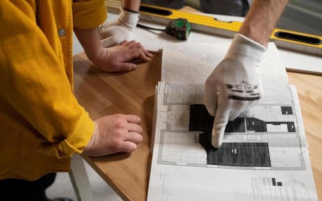 Trabajador y cliente miran un plano durante la reforma de un apartamento.