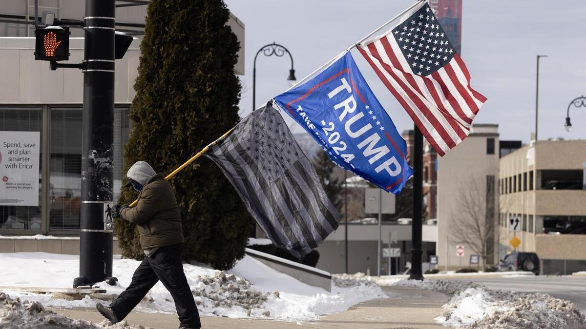 Un seguidor de Trump lleva una bandera del expresidente en Manchester, Nuevo Hampshire.