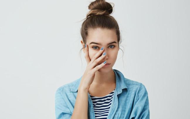 Una mujer se lleva la mano a la cara en un gesto de vergüenza.