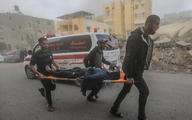 Tres palestinos trasladan a una mujer herida en un ataque israelí.