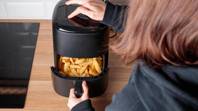 Una niña se está preparando unas patatas en la freidora.