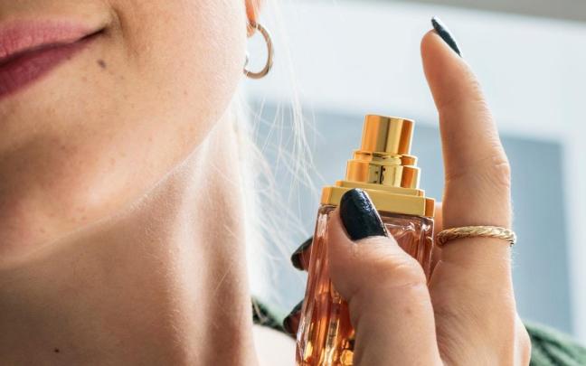 Una mujer se aplica perfume en el cuello.