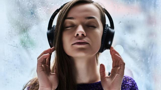 Una mujer, muy concentrada, escucha música a través de sus auriculares.