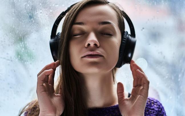 Una mujer, muy concentrada, escucha música a través de sus auriculares.