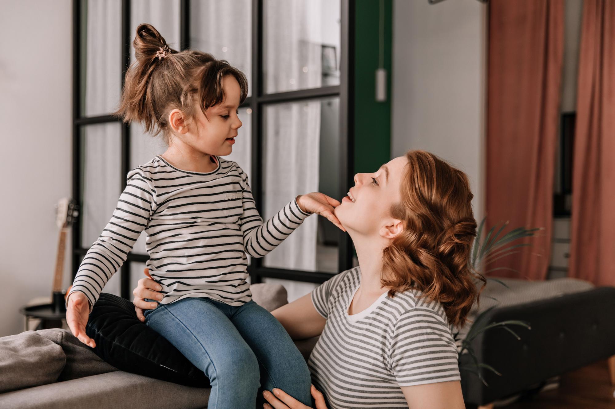 Una madre cómplice conversa con su hija mientras ambas comparten un momento de confianza.
