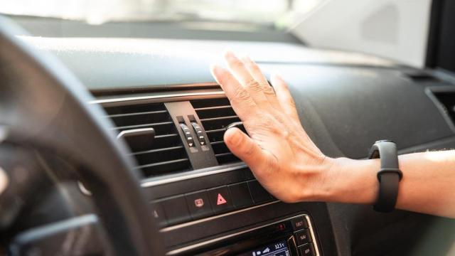 Una persona comprueba el aire acondicionado del coche en un día de calor.