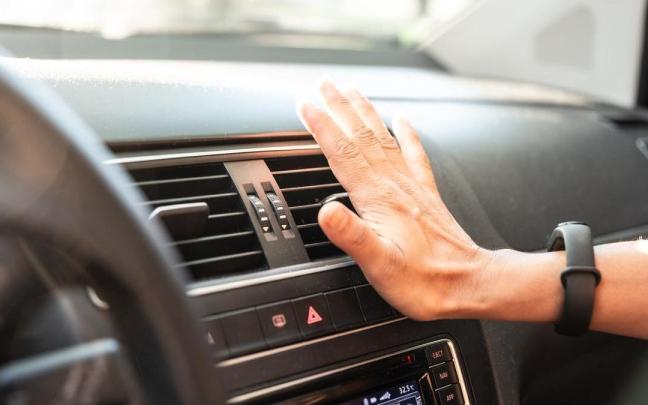 Una persona comprueba el aire acondicionado del coche en un día de calor.