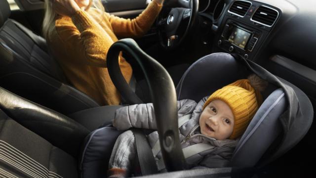 Bebé en el asiento delantero de un coche.