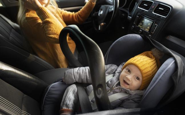 Bebé en el asiento delantero de un coche.