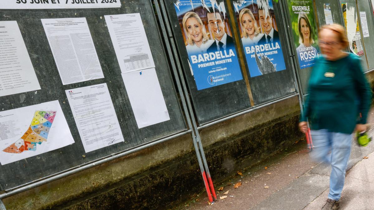 Una mujer pasa por delante de carteles electorales de Marine Le Pen y Jordan Bardella.