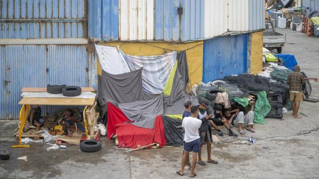 Varios inmigrantes se protegen de la lluvia con telas y lonas, en Ceuta.