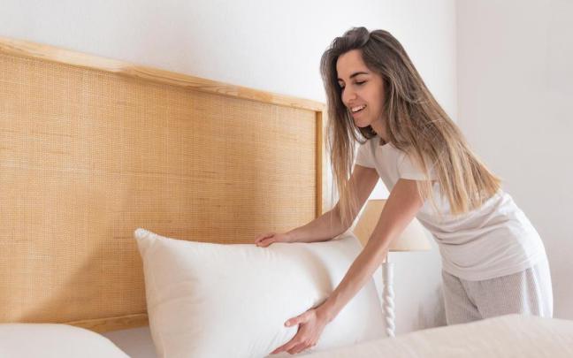 Chica coloca la almohada en la cama.