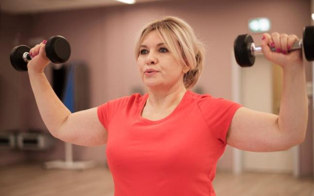 Una mujer hace entrenamiento de fuerza en un gimnasio.