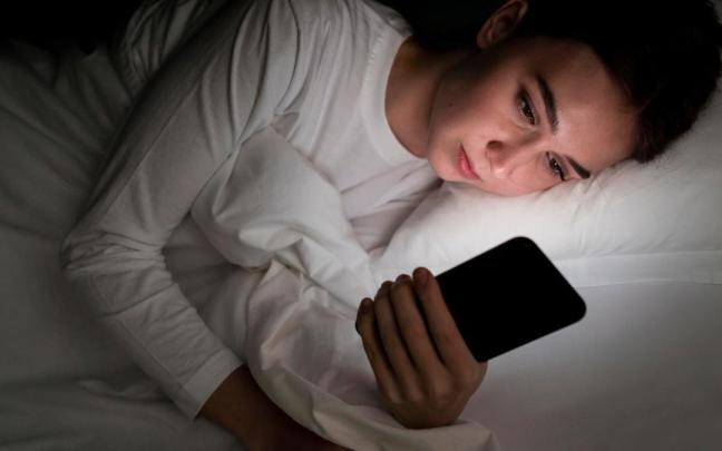 Una adolescente mirando un móvil.