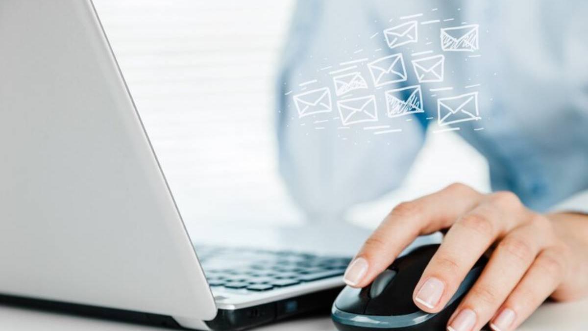 Mano de una mujer en el ratón de su ordenador portátil revisando su correo electrónico.