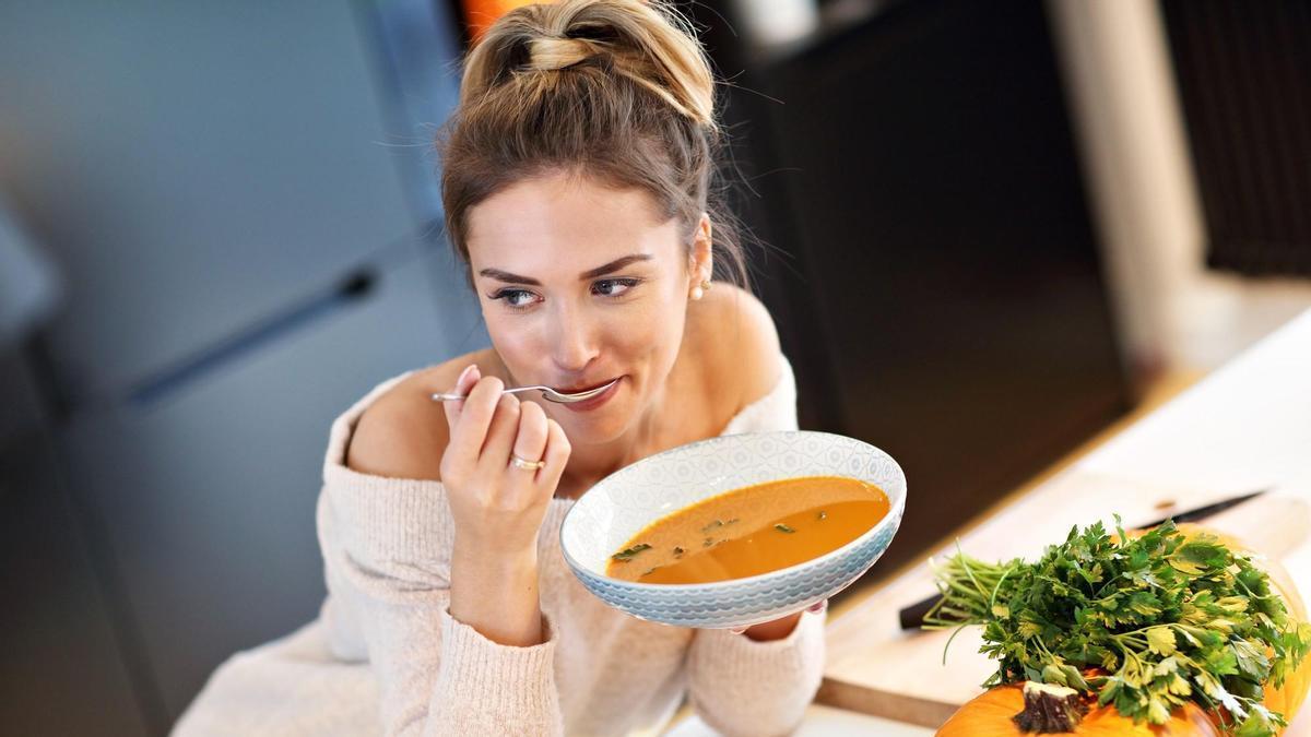 Una mujer toma un plato de sopa de calabaza.