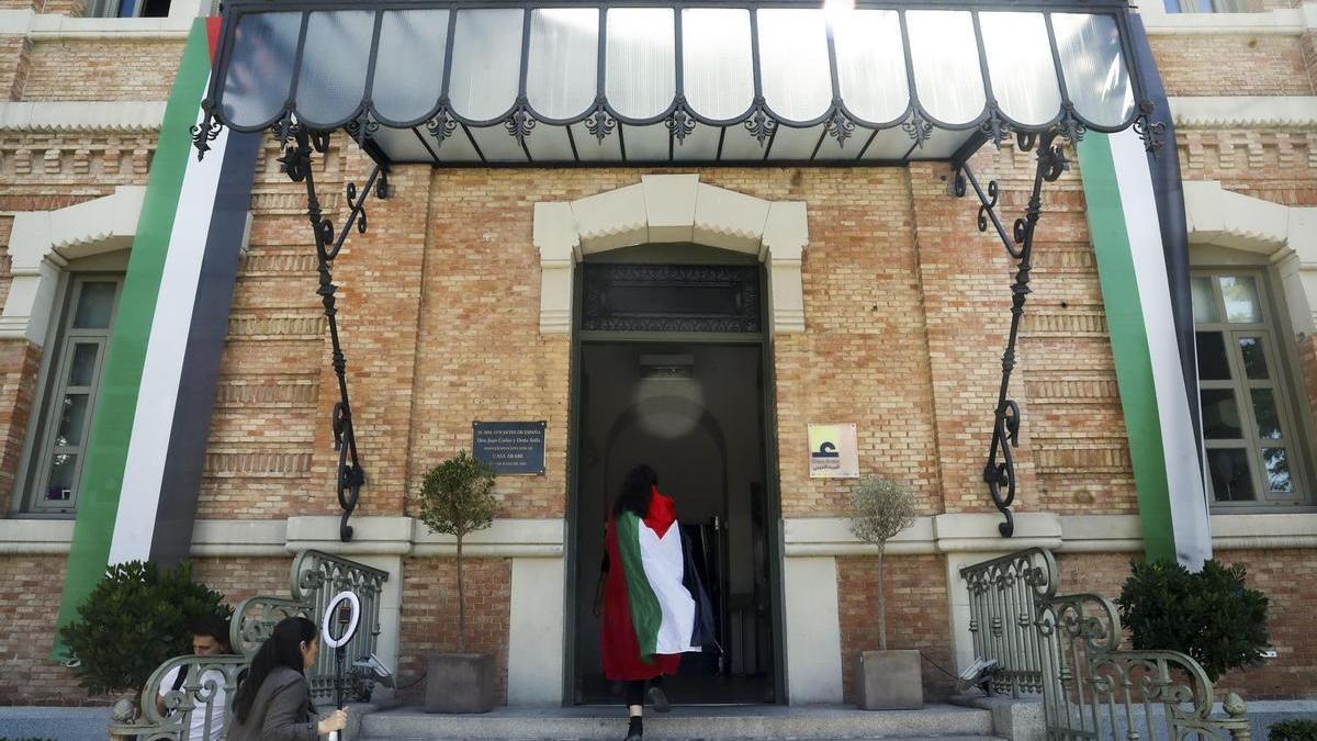 Una joven con la bandera palestina entra en la Casa Árabe en Madrid.