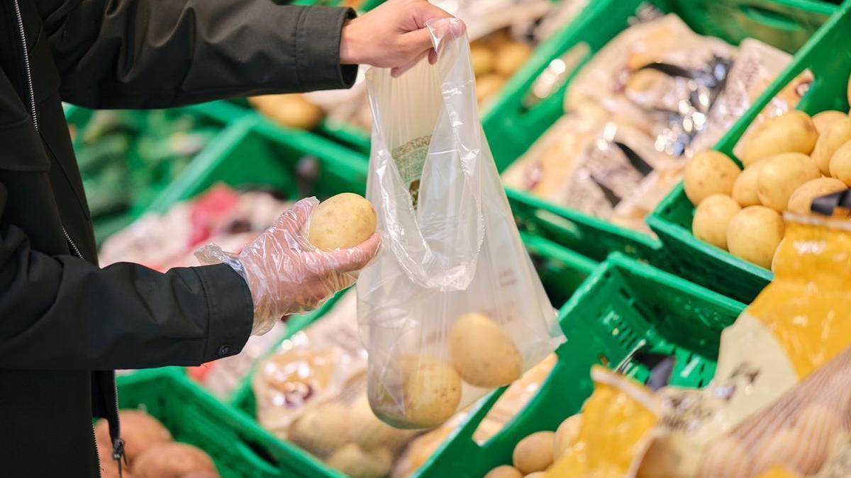 Una persona compra patatas en un supermercado.