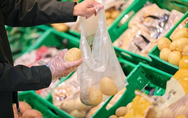 Una persona compra patatas en un supermercado.