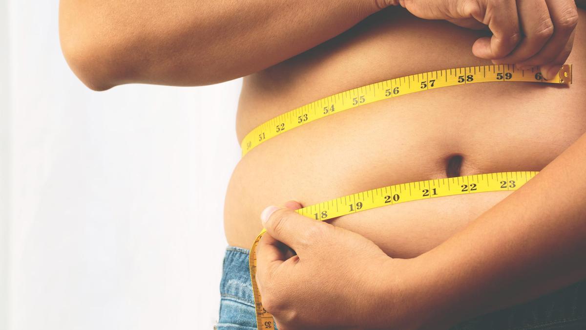 Un hombre se mide el contorno con una cinta métrica.