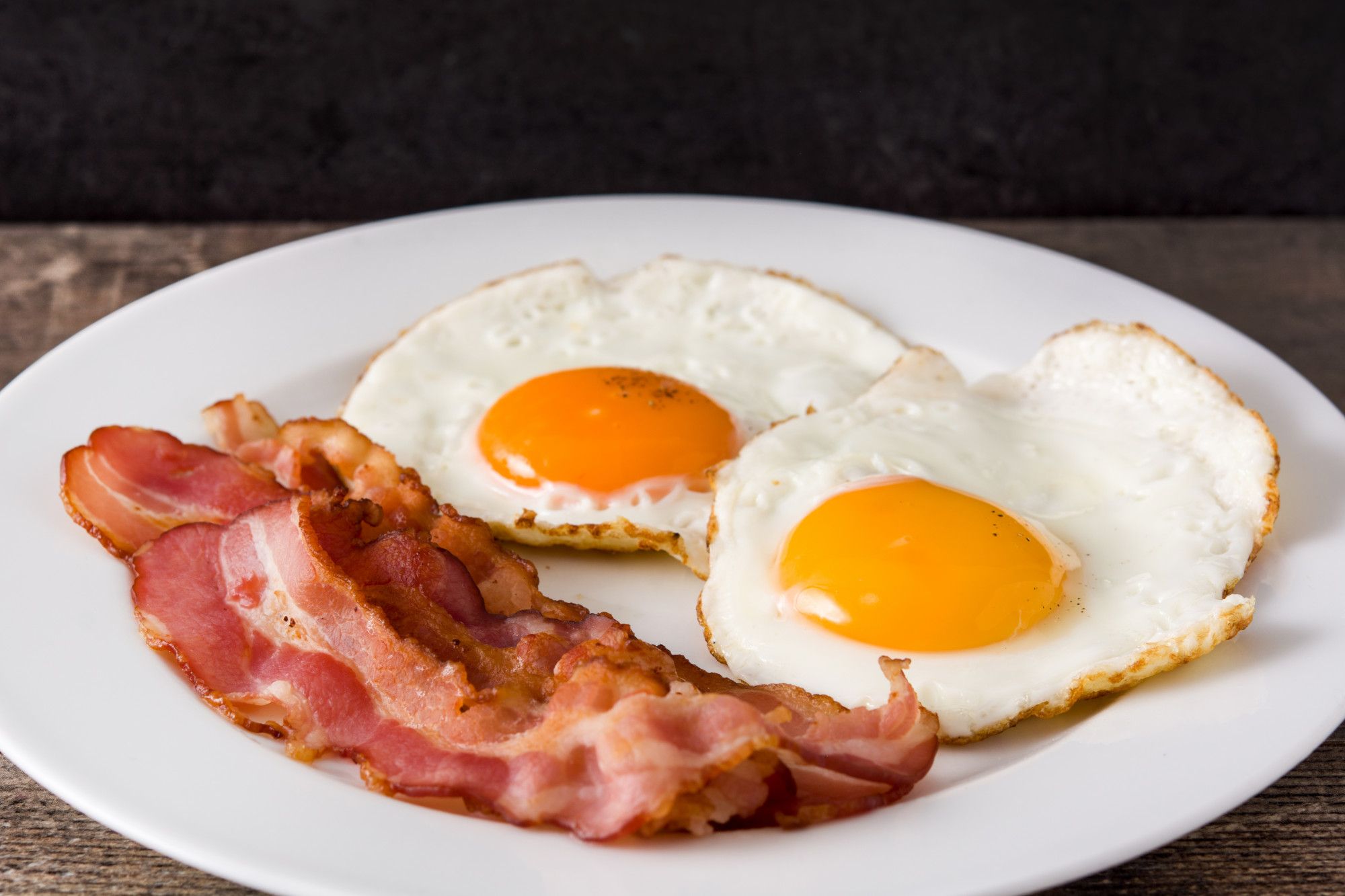 Dos apetitosos huevos fritos con bacon.