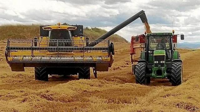 Una cosechadora y un tractor en un campo de cereal, en una imagen de archivo Una cosechadora y un tractor en un campo de cereal, en una imagen de archivo