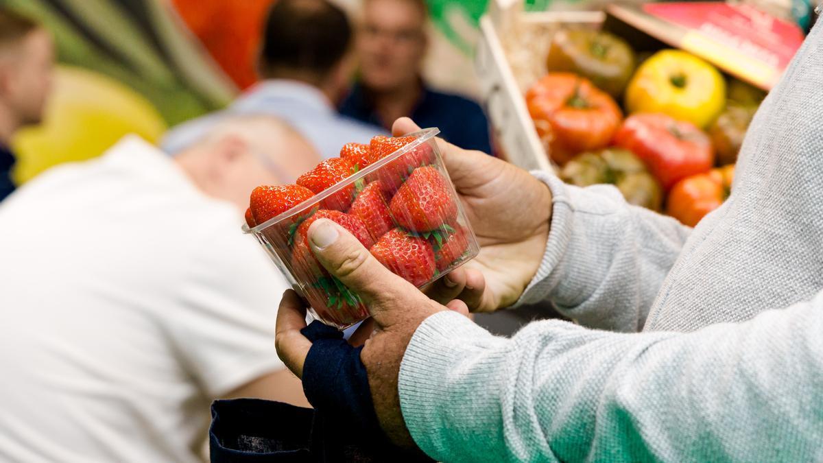 Un hombre compra una caja de fresas
