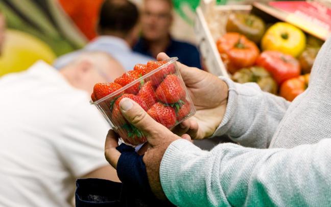 Un hombre compra una caja de fresas