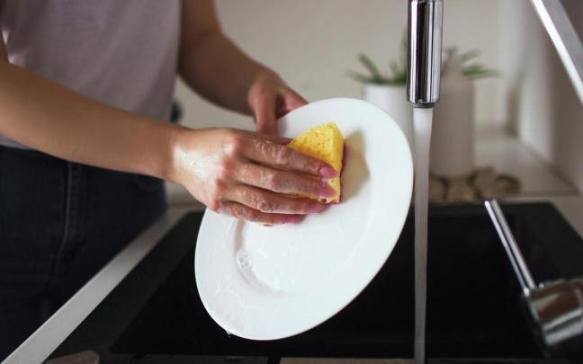 Una mujer friega un plato sin protección en las manos.